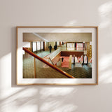 A large-scale Studio Edition print of 'Hotel Okura – Salary Men' framed in a minimalist home office, highlighting the warm mid-century tones of the Japanese architecture.