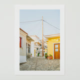 A close-up of the Siesta in Samos print, showing the clear blue sky and the details of the village houses on high-quality paper.